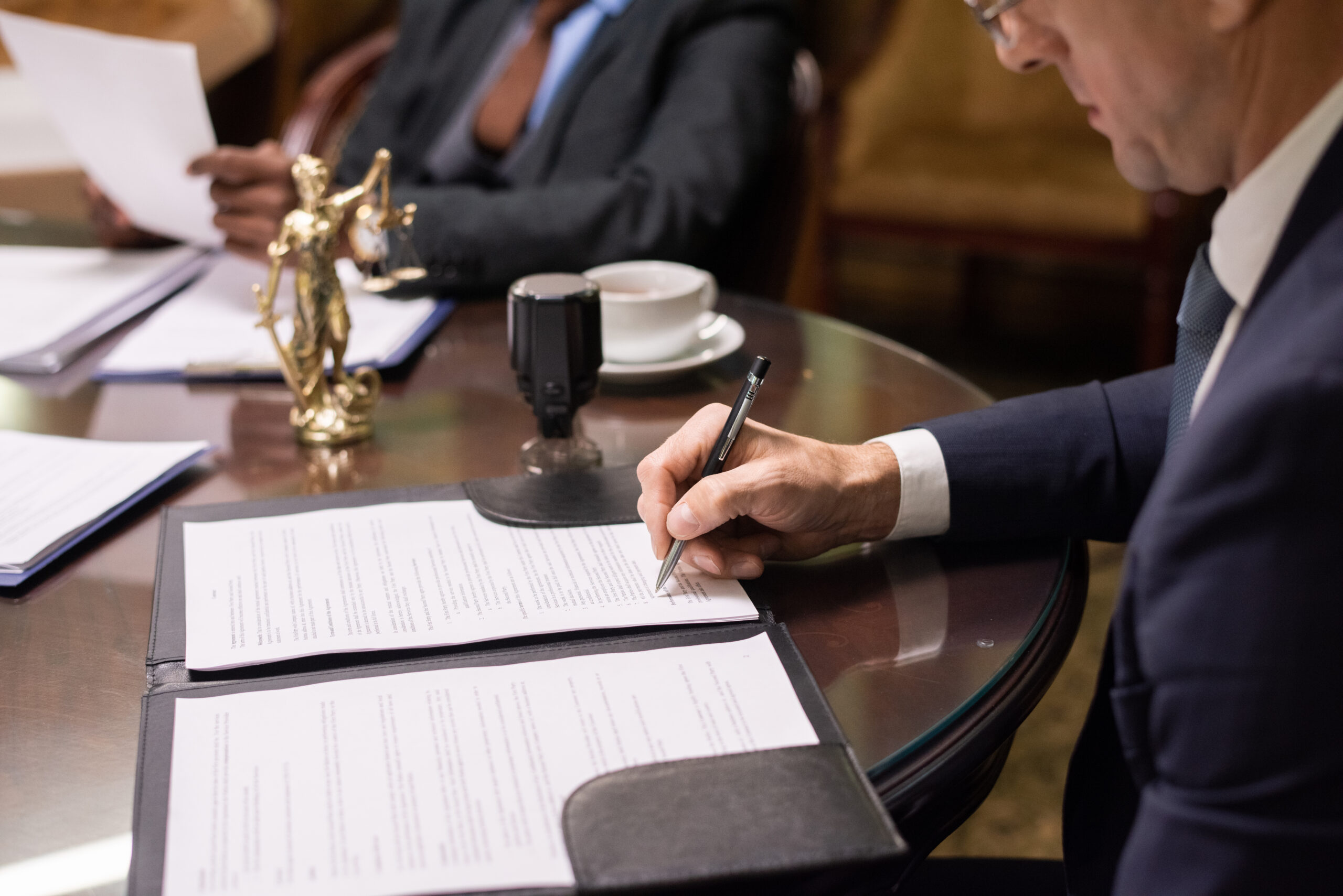 Notario trabajando en una oficina revisando documentos legales, con libros de Derecho Notarial y papeles relacionados con escrituras y protocolos